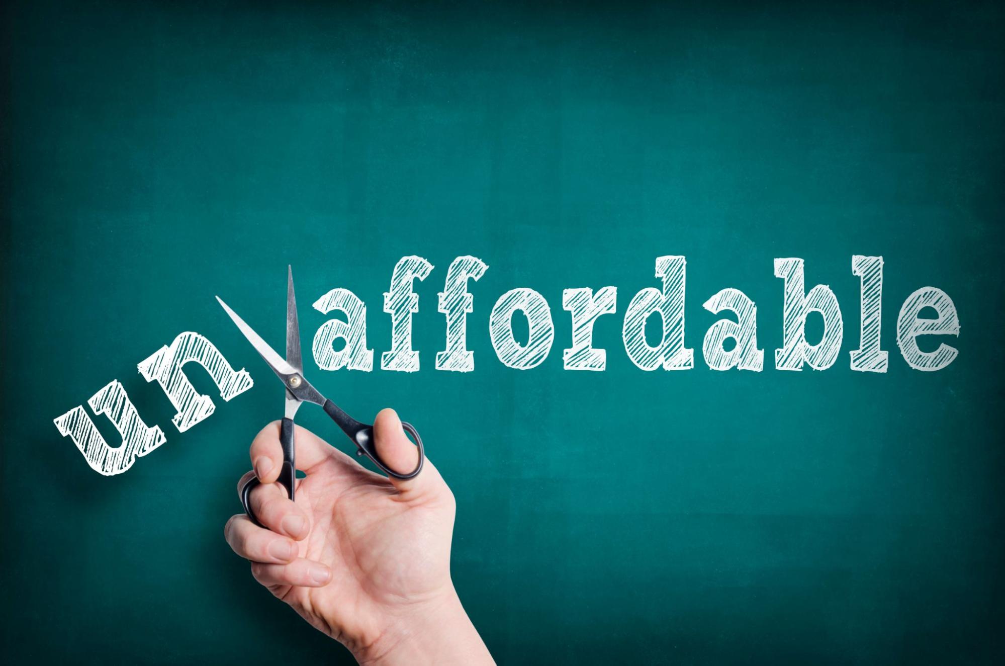 Hands holding scissors cutting "un" off of "affordable"